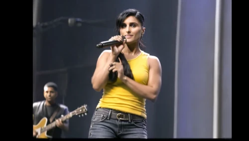 myna,birce akalay,live performance,yellow taxi,sleeveless shirt,veena,playback,humita,yellow and black,bulbul,shama,kamini,yellow background,live concert,yellow jumpsuit,melody,student with mic,singer,singing,yellow