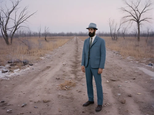 standing man,walking man,conceptual photography,arid land,suitcase in field,surrealistic,dead earth,andreas cross,desertification,man's fashion,men's suit,deforested,stilt,stilts,straw man,lincoln blackwood,itinerant musician,smoking man,rasputin,surrealism,Photography,Documentary Photography,Documentary Photography 07