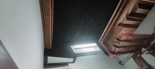 wooden beams,ceiling construction,wooden stairs,dark cabinetry,attic,wooden stair railing,skylight,structural plaster,daylighting,concrete ceiling,ceiling light,ceiling ventilation,ceiling lighting,under-cabinet lighting,laminated wood,outside staircase,stucco ceiling,laminate flooring,vaulted ceiling,roof lantern