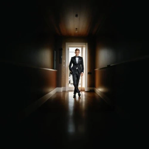 hallway,a dark room,eleven,slender,hallway space,corridor,dress walk black,dark suit,the threshold of the house,spy,spy visual,woman in menswear,album cover,in the shadows,in the dark,hotel man,basement,secret agent,man silhouette,in the door
