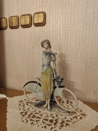 dollhouse accessory,woman bicycle,vintage doll,paper art,decorative figure,girl with a wheel,miniature figure,velocipede,doll kitchen,antique background,3d figure,bicycle,doll figure,handmade doll,figurine,artist doll,painter doll,wooden figure,antique style,statuette