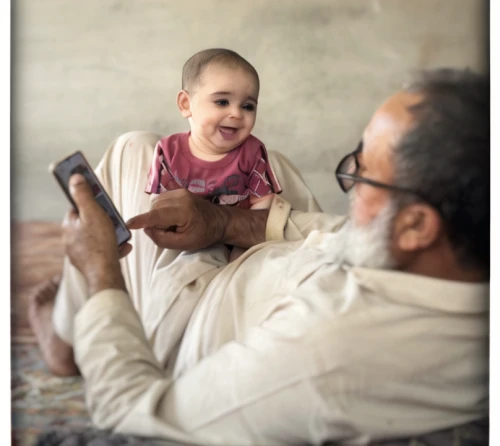 father with child,photographing children,grandchild,granddaughter,little girl reading,father's love,next generation,photos of children,muhammad,kabir,middle eastern monk,holding ipad,sheikh,pediatrics,mobile click,grandfather,photographs,child playing,the integration of social,shehnai