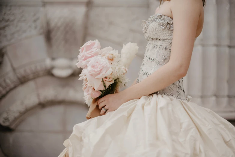 a woman wearing a wedding gown and holding a bouquet of flowers