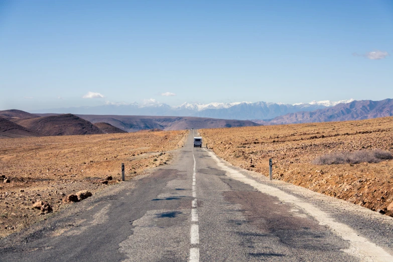 an empty highway leading through the mountains