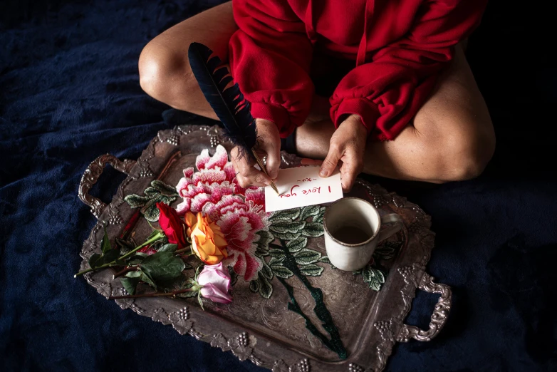 a woman sitting in front of a tray of flowers  a cake