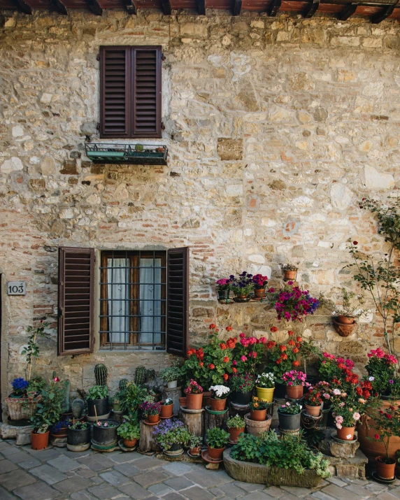 a brick building with several flowers and pots around it