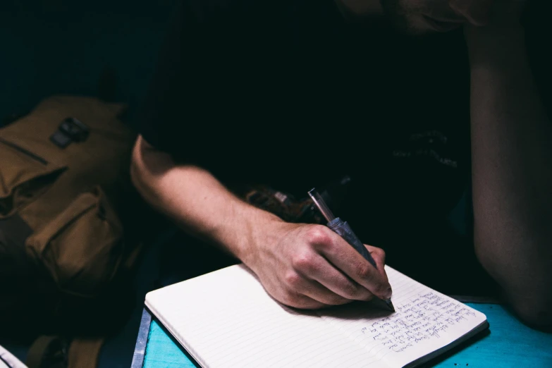 a man sitting at a table writing on his notebook