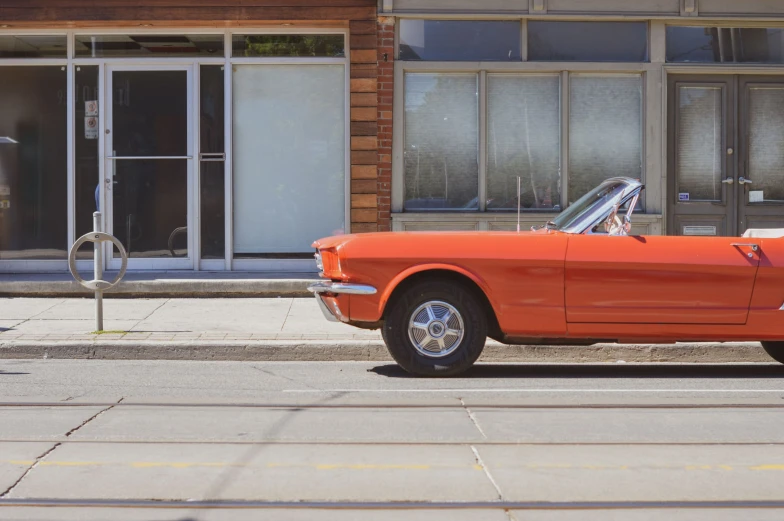 an orange car parked on a sidewalk next to a brick building