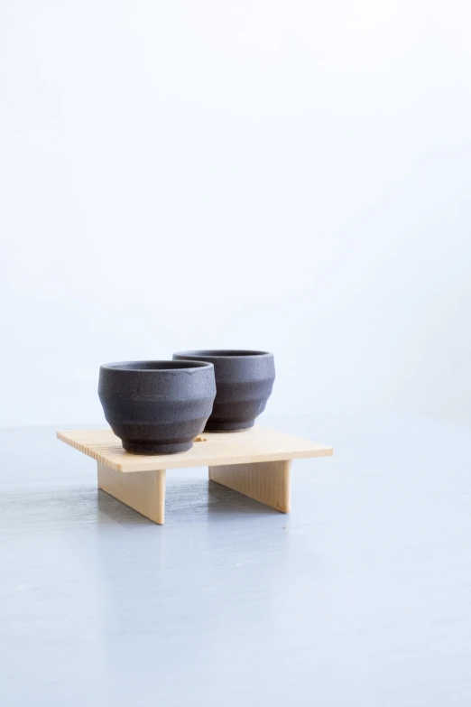 two black bowls on wooden base in the corner
