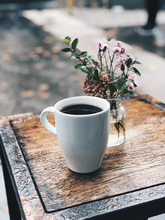 a cup of coffee and a vase with flowers on the table