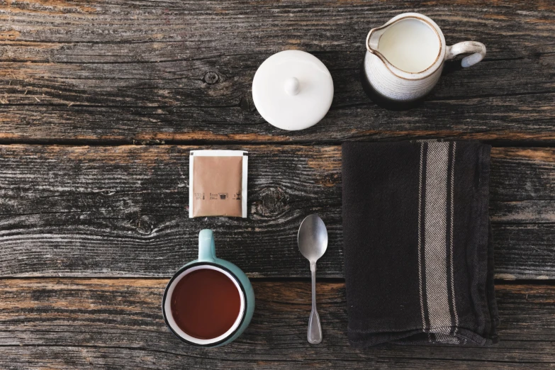 a table topped with an empty tea cup, candle and kitchen items