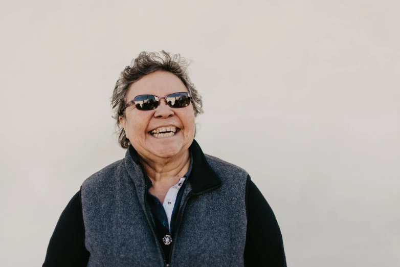 an old woman wearing sunglasses smiling for the camera