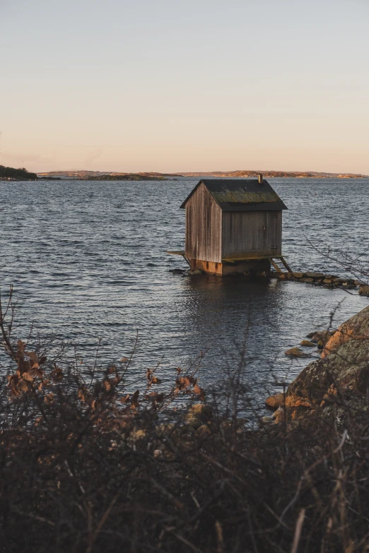 an out house stands on the edge of the lake