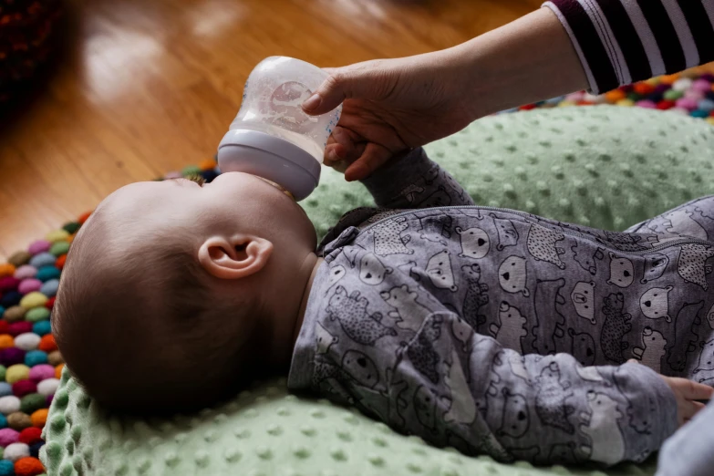 a baby has a bottle in his mouth while being fed by an adult