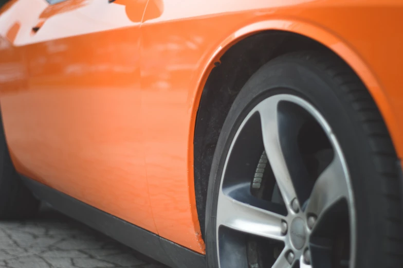 the front wheel of an orange sports car