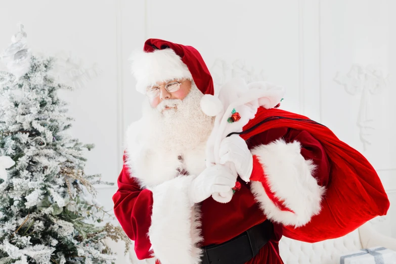 a santa clause carrying a bag in front of a christmas tree