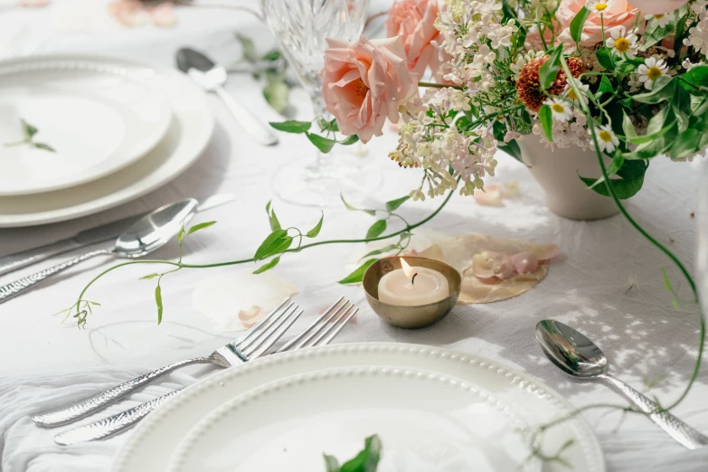 the table is set with many plates, silverware and flowers