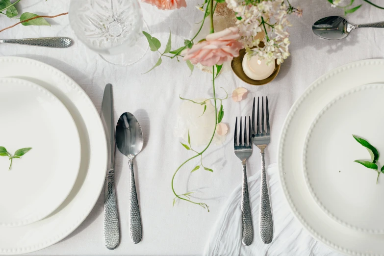 a table set up with utensils and flowers