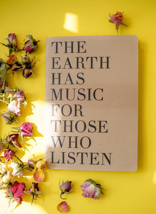 an upside down view of a white sheet with black lettering that says the earth has music for those who listen on yellow background