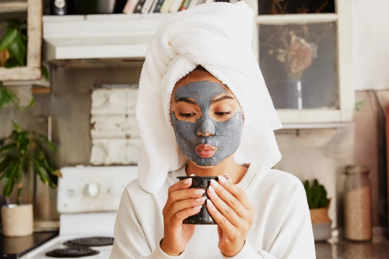 woman putting face mask on and covering her face with towels