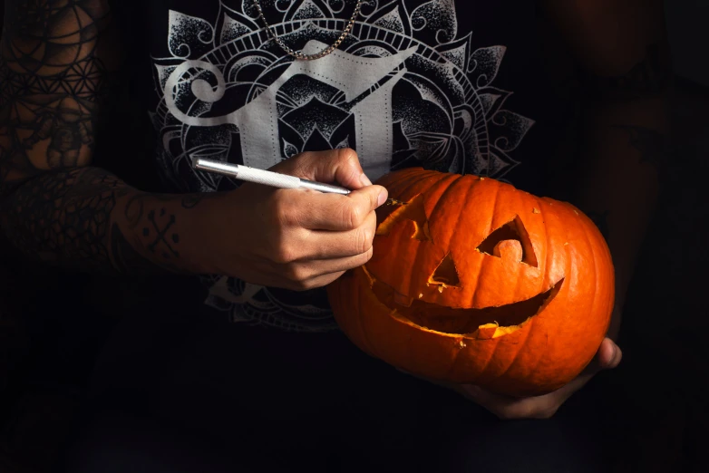 a person is holding a pumpkin and writing soing