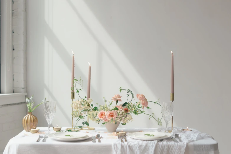 a close up of flowers and candles near a dining table