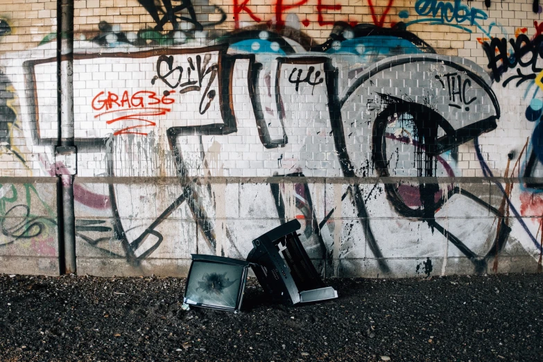 a couple of electronic devices sitting next to a graffiti covered wall