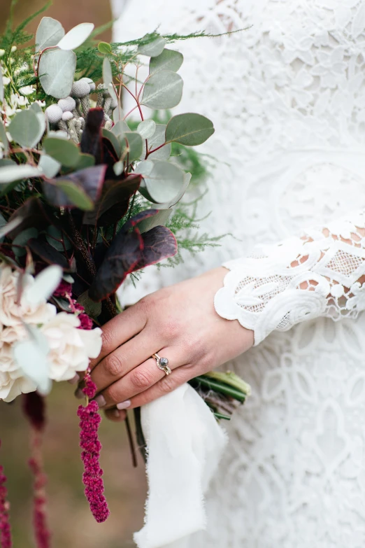 a woman is holding flowers and greenery outside