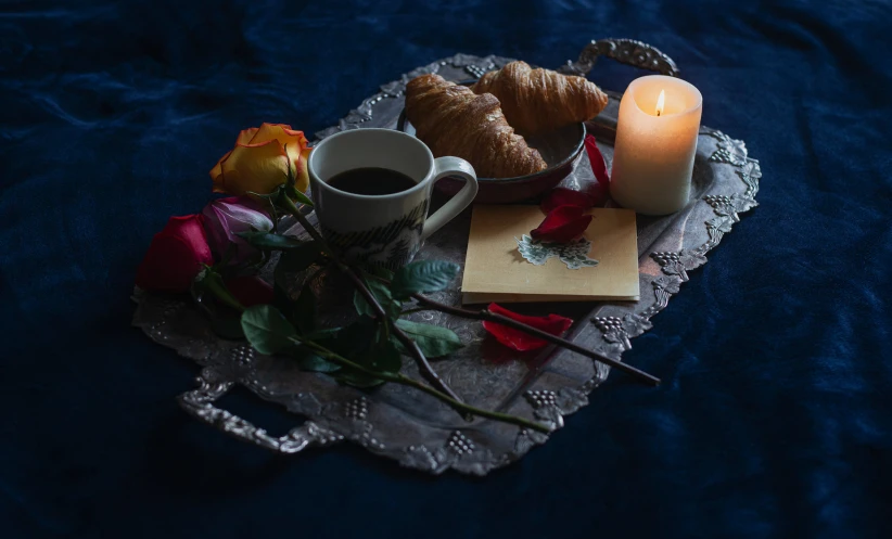 a candle, flowers and pastry on a doily