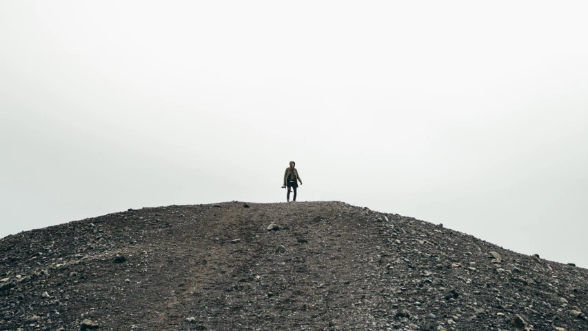 a person stands on the top of a mound of dirt
