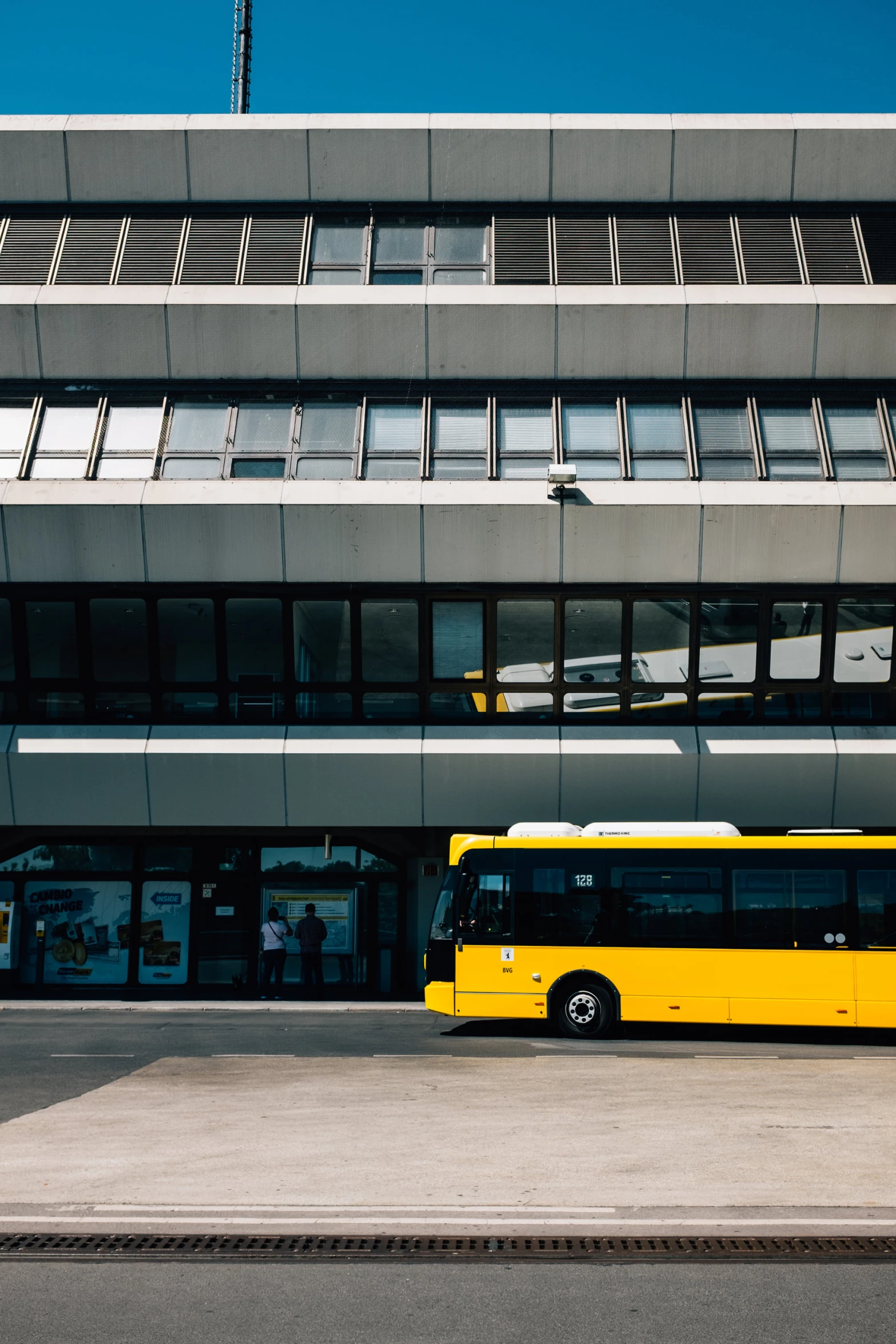 a big yellow bus sitting in front of a very tall building