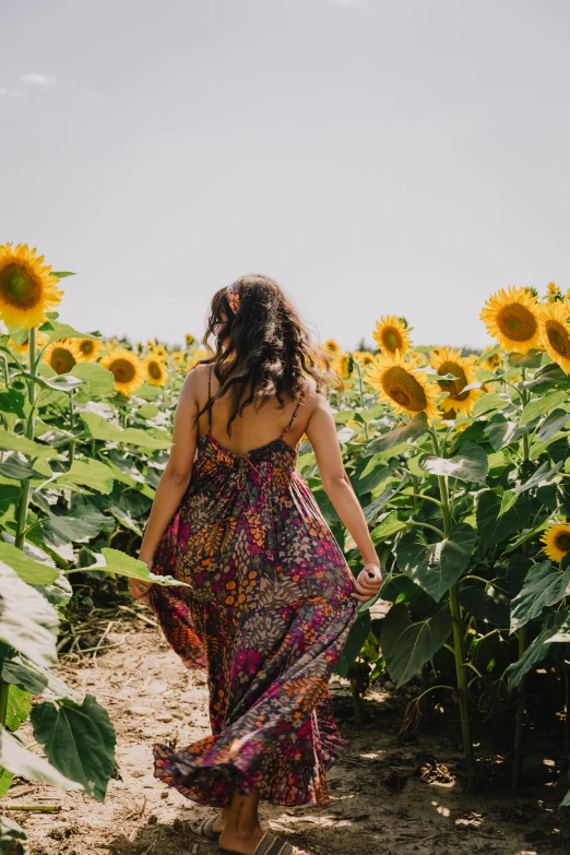 a woman walking through a sunflower field