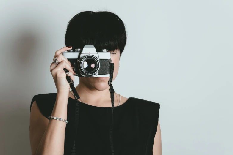 woman with hair covering eyes using camera to take pictures