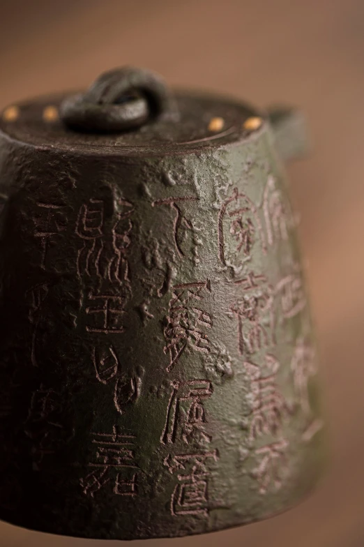 a metal bell with ancient writing and a string at the bottom