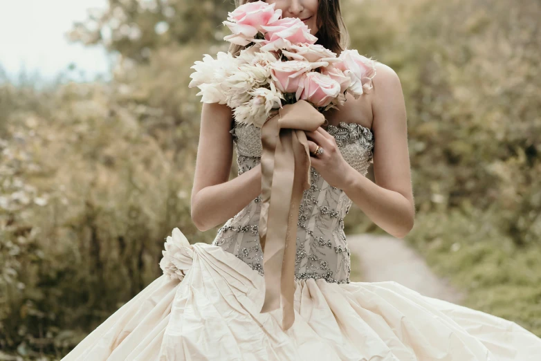 a beautiful woman wearing a wedding gown carrying flowers in her hand