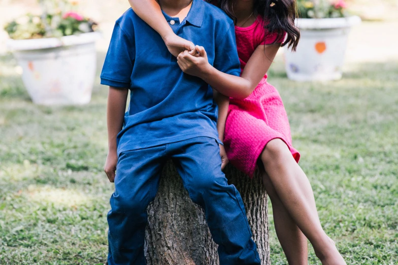 a boy and girl on a tree in the park