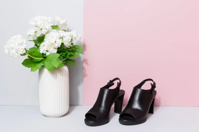 a pair of shoes sitting beside a vase of flowers