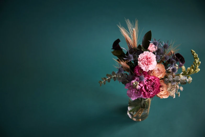 flowers and grasses in a vase sitting on green