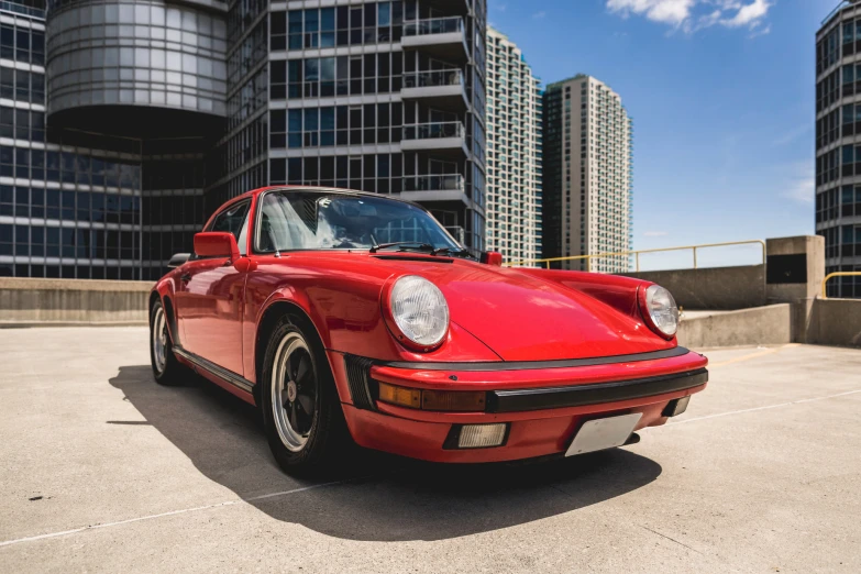 a red porsche parked in front of a very tall building