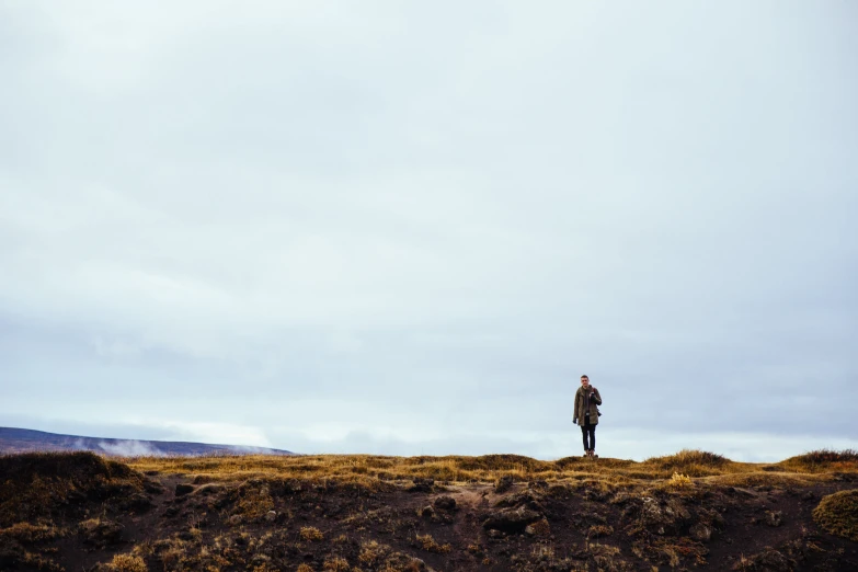 a lone man stands on a hill, looking out