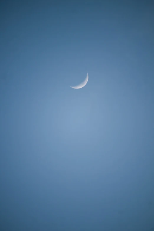 a po of a half moon and a clear blue sky
