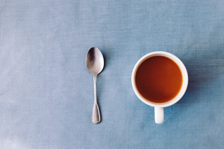 coffee with spoon next to it and a bowl on the table