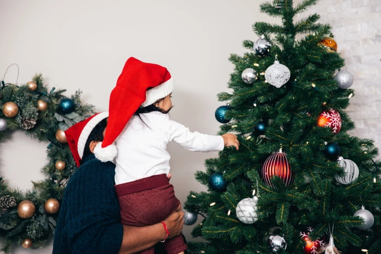 a boy is decorating the christmas tree in his home