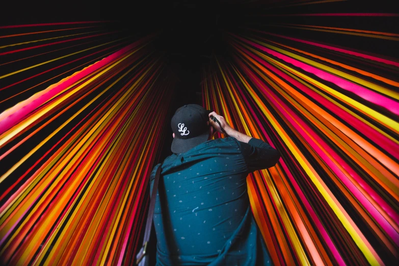a man in black jacket standing inside of a rainbow colored tunnel