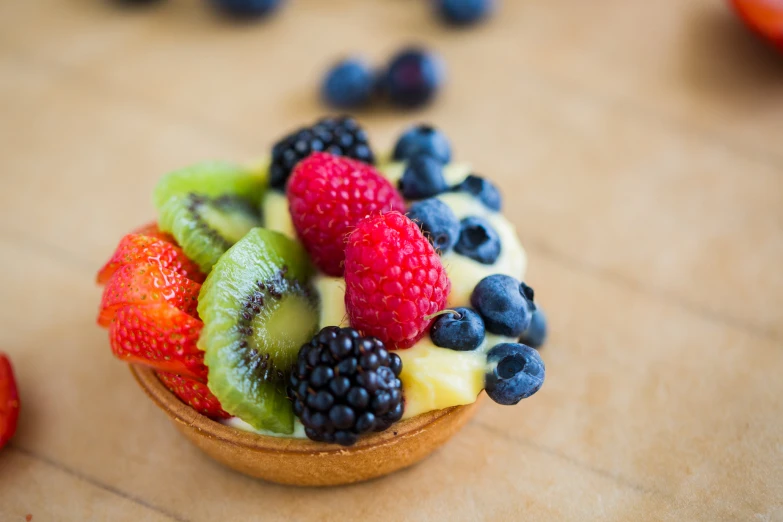 a small cupcake with kiwis, berries, and bananas