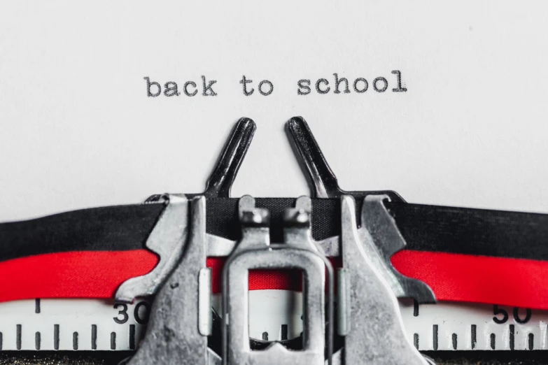 a black and red typewriter with white paper that says back to school on it