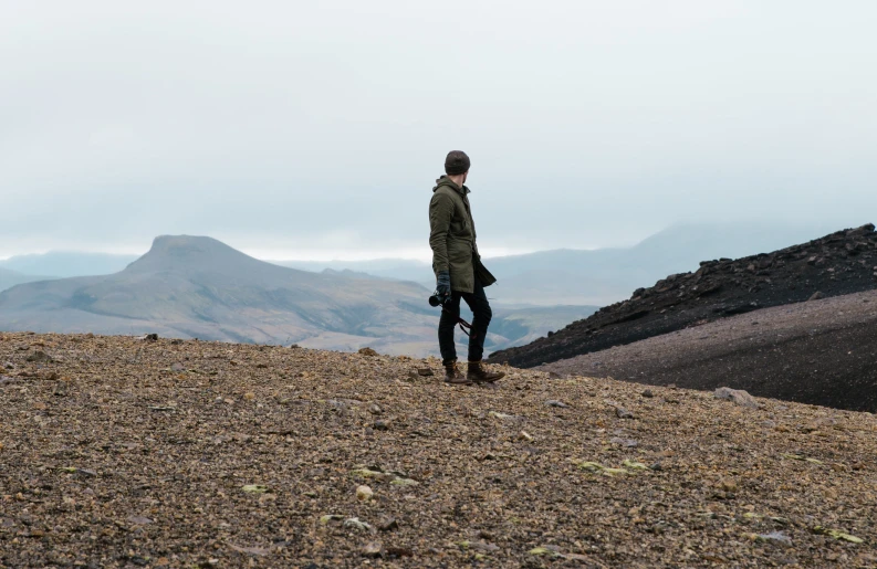 a person standing alone on a hill looking across a valley