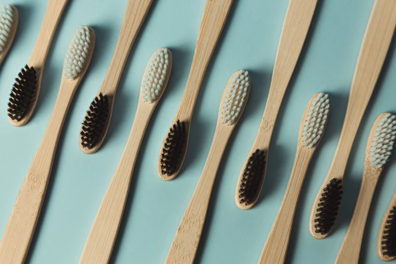 many toothbrushes arranged together in rows on a blue surface