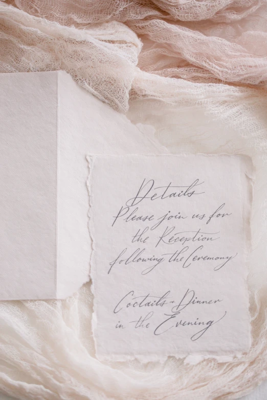 a wedding ceremony card laying on some white linen