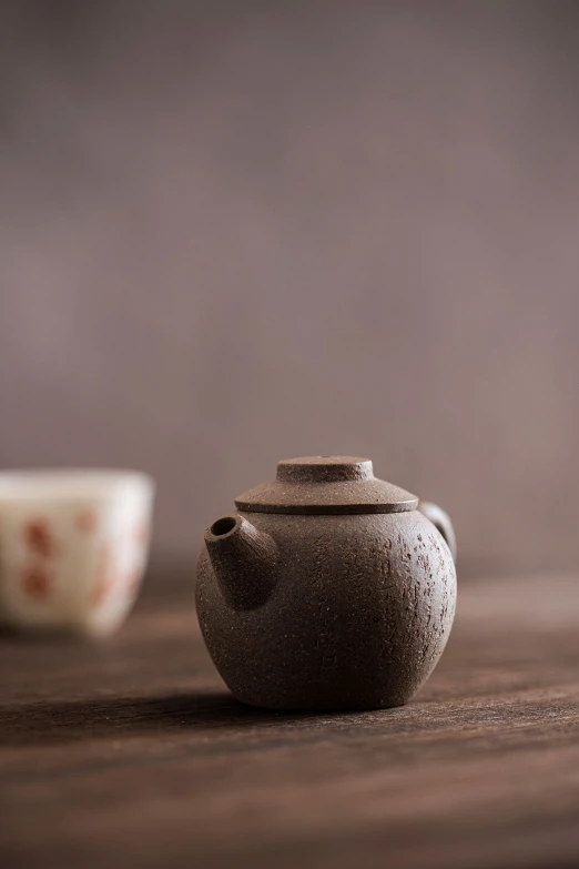 a small teapot and cup on a wooden table